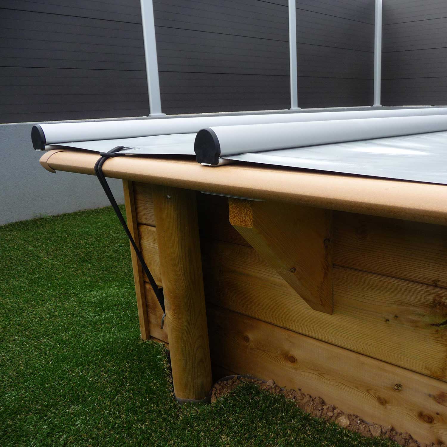 Automatisiertes Poolabdeckungssystem mit einziehbarem Mechanismus auf einer Holzkonstruktion.