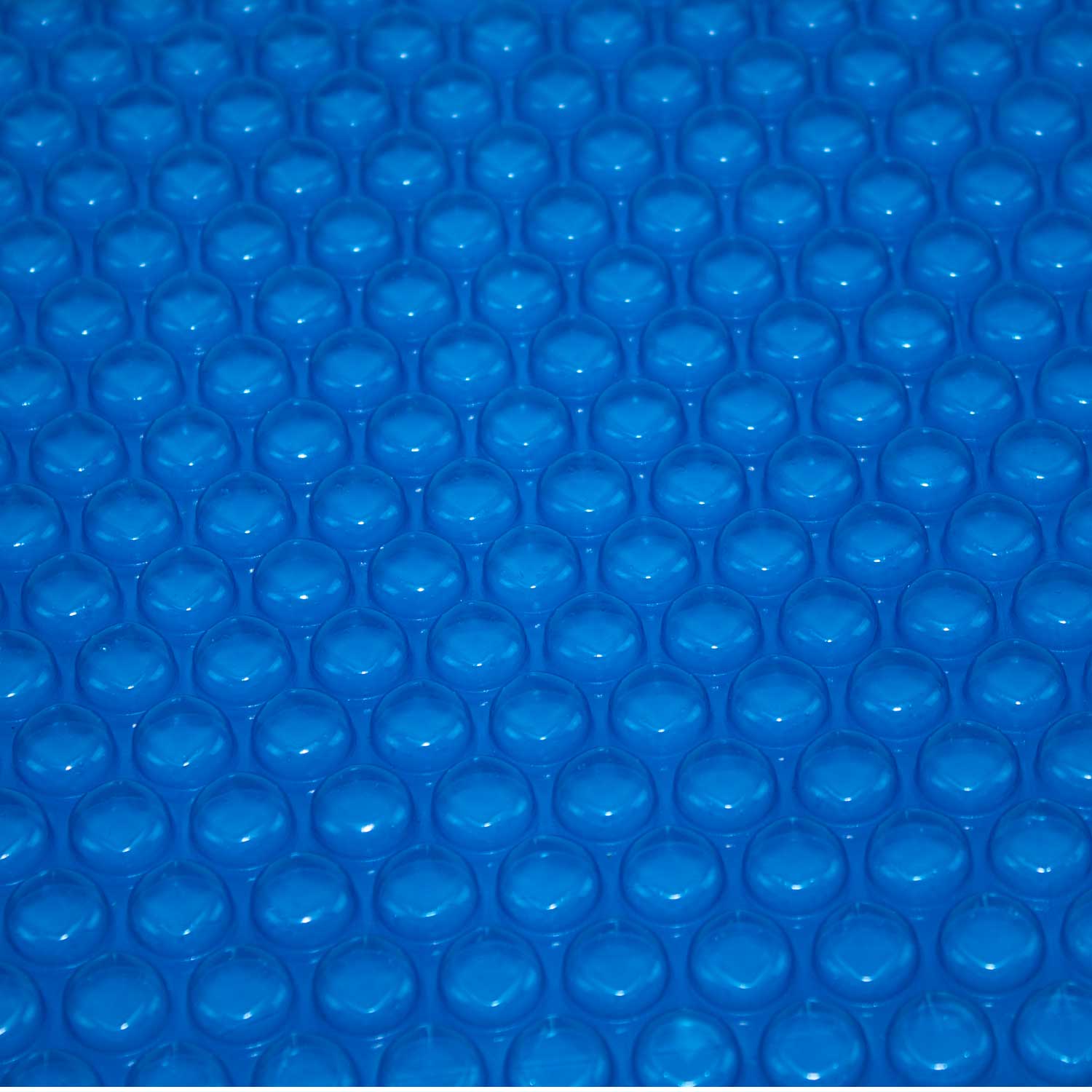 Nahaufnahme einer blauen Sprudelbeckenabdeckung, die ein sich wiederholendes Muster aus luftgefüllten Blasen zeigt.