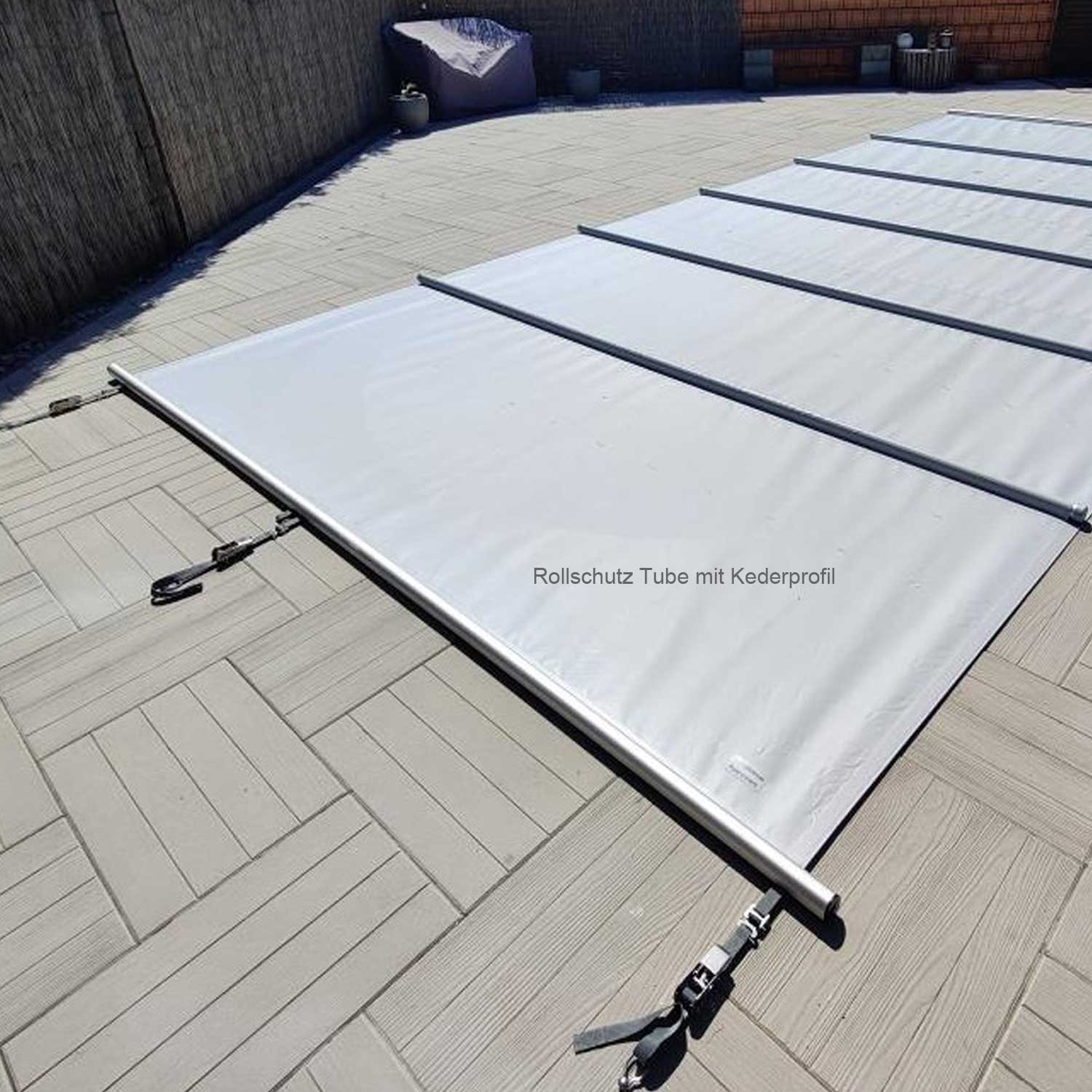 Auf einer gefliesten Terrassenfläche im Außenbereich liegt ein geschlossenes, graues Poolüberdachungssystem mit Metallstützen.