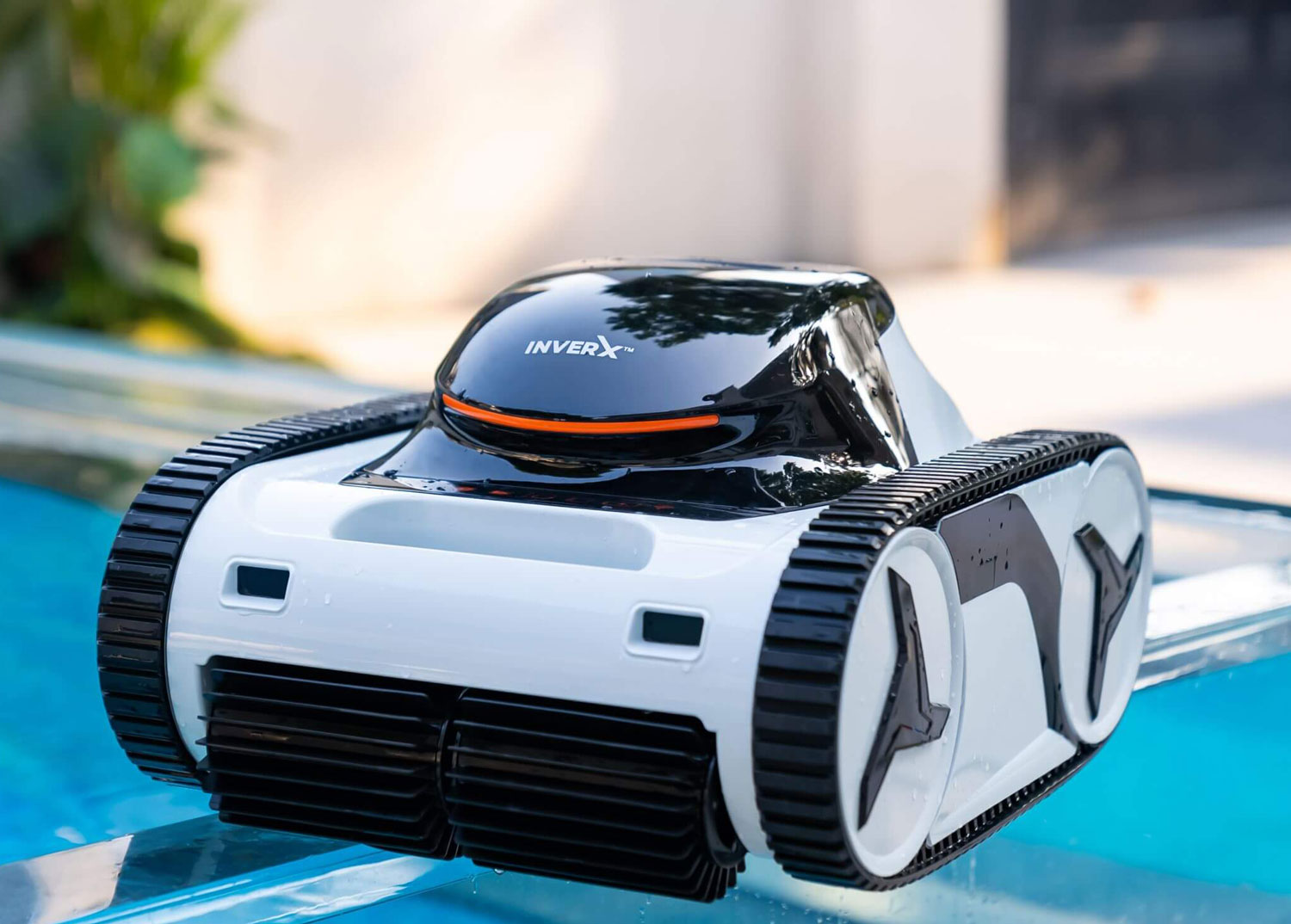 Nahaufnahme eines weiß-schwarzen Roboter-Poolreinigers mit Tankauftritten, der auf dem Rand eines Pools ruht.