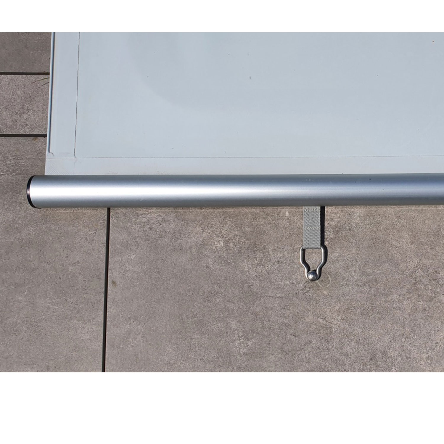 Detail einer weißen Poolabdeckung mit einer silbernen Aluminiumrolle und einem grauen Spannband.