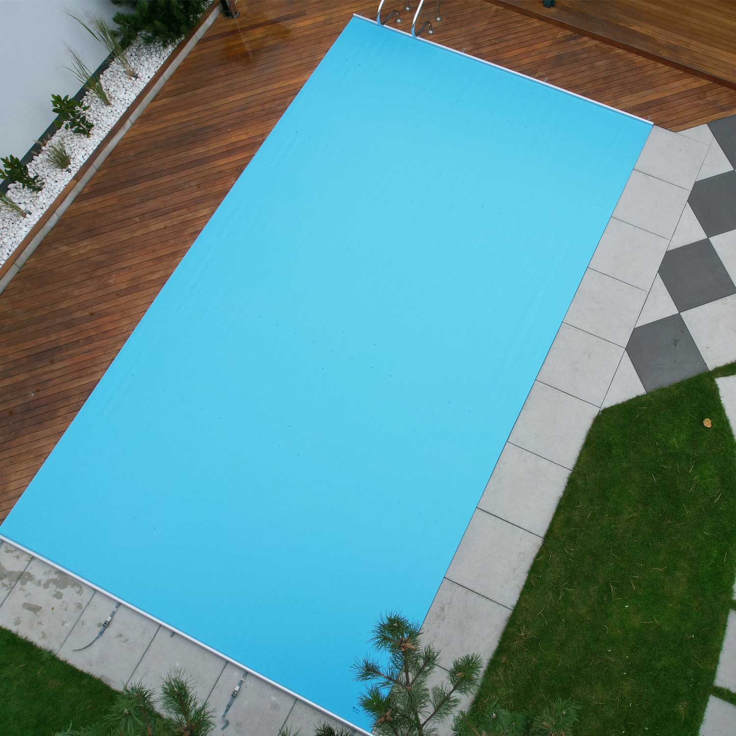 Luftaufnahme eines rechteckigen Schwimmbeckens mit installierter hellblauer Sicherheitsabdeckung.