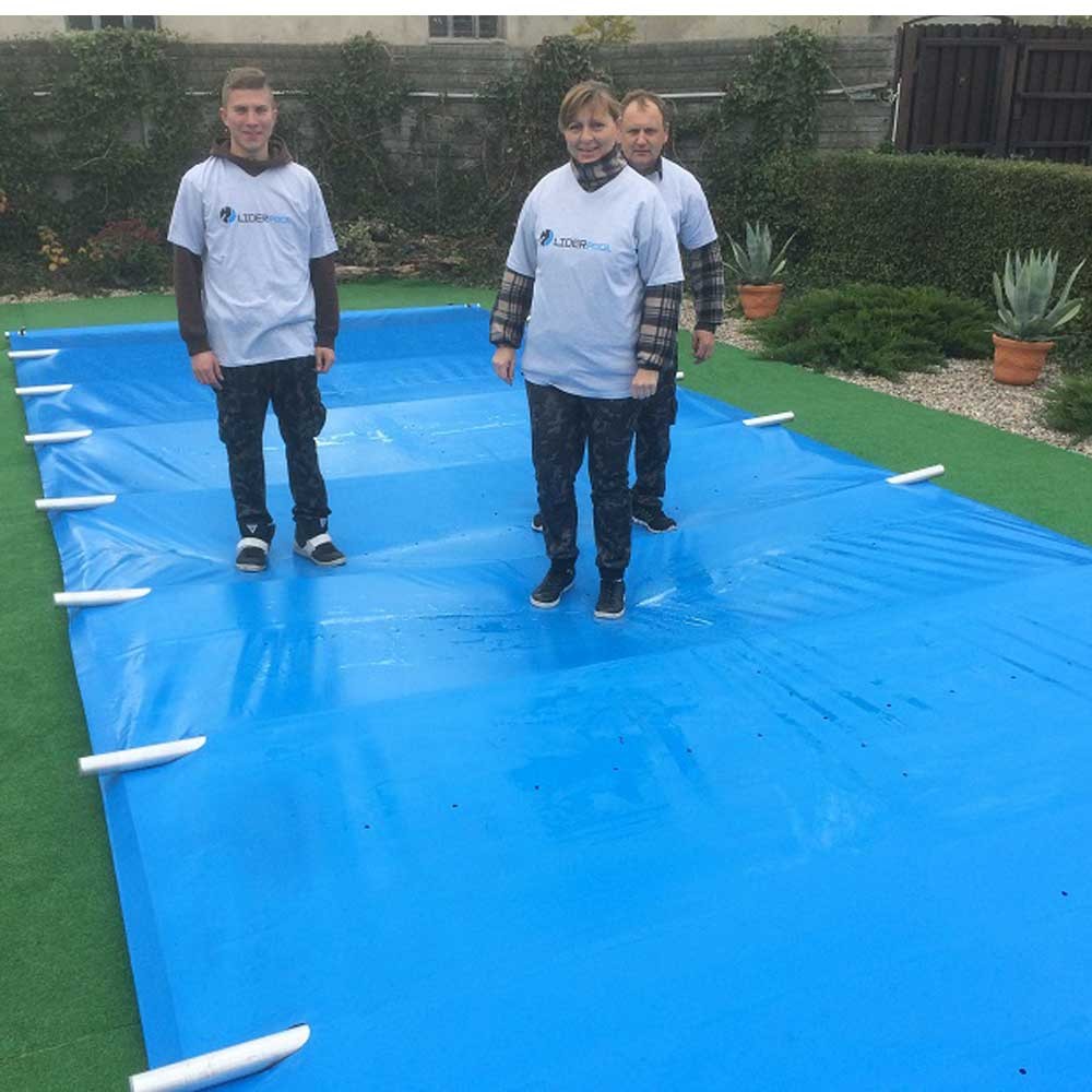 Die Installation der blauen Pool-Sicherheitsabdeckung wird mit drei Installateuren gezeigt, die auf der Abdeckungsoberfläche stehen.