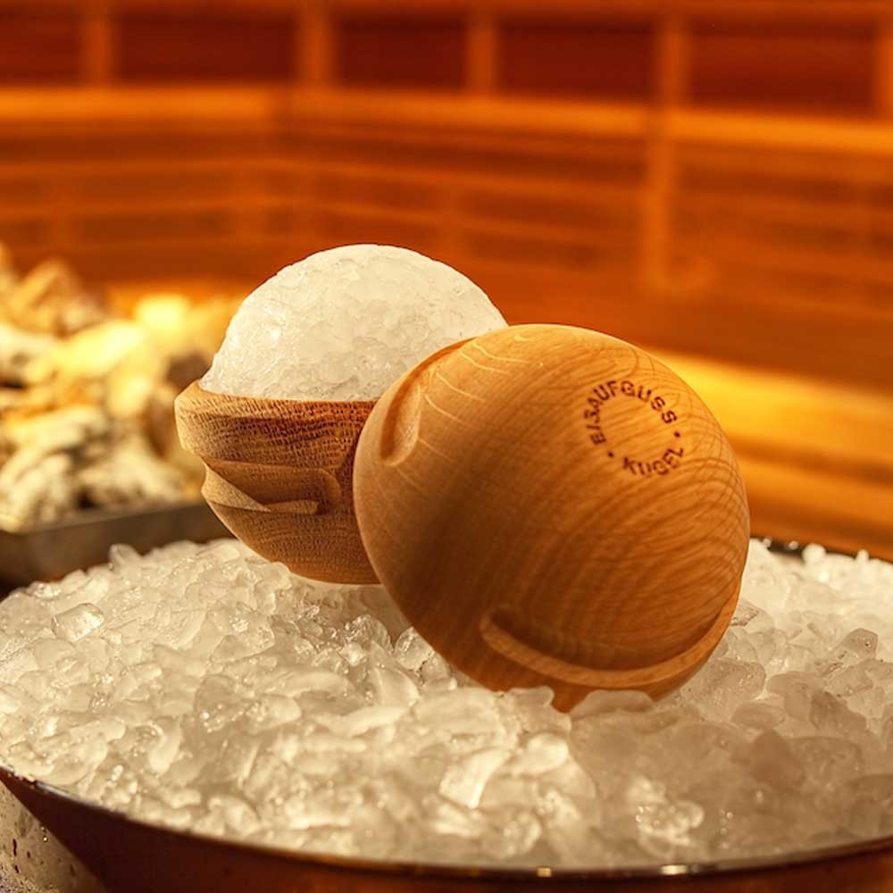 Nahaufnahme von Saunaaufgussbällen, von denen einer mit Eis gefüllt ist und auf einem Bett aus zerstoßenem Eis liegt.