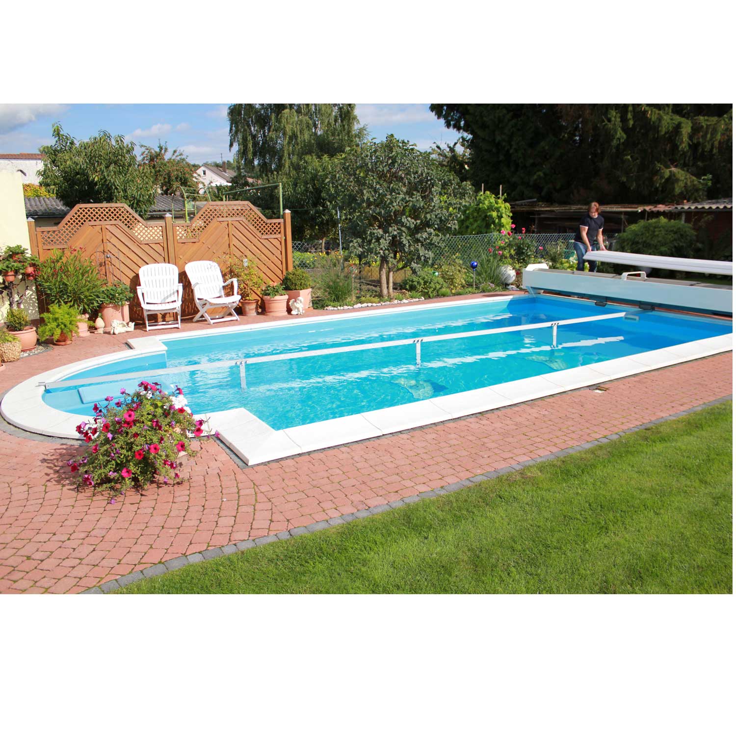 Das Bild zeigt einen rechteckigen, in den Boden eingelassenen Swimmingpool mit einem teilweise sicheren Poolabdeckungssystem.