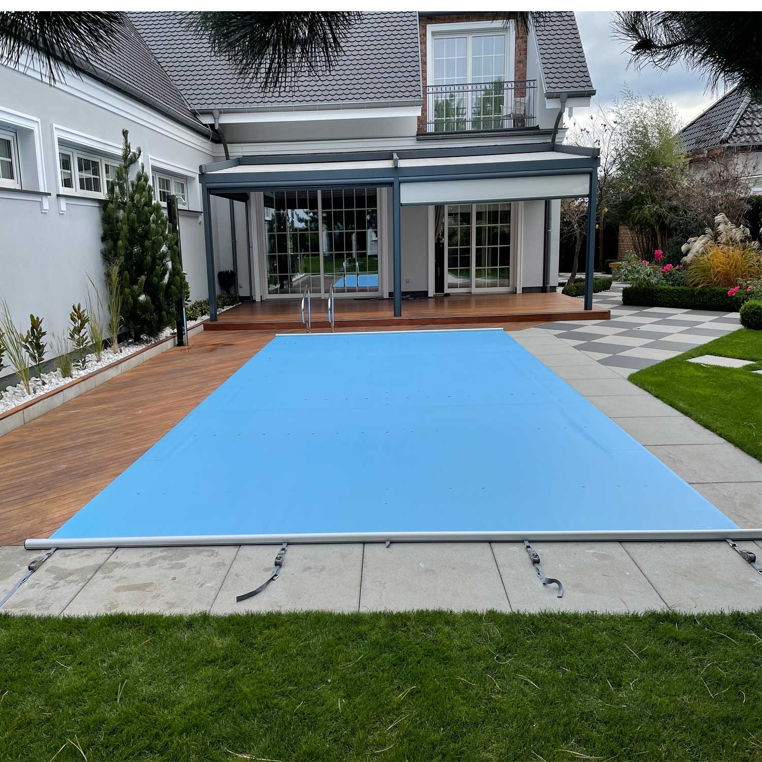 Rechteckiger Swimmingpool mit blauer Sicherheitsabdeckung, installiert in einem Wohngebiet im Freien.