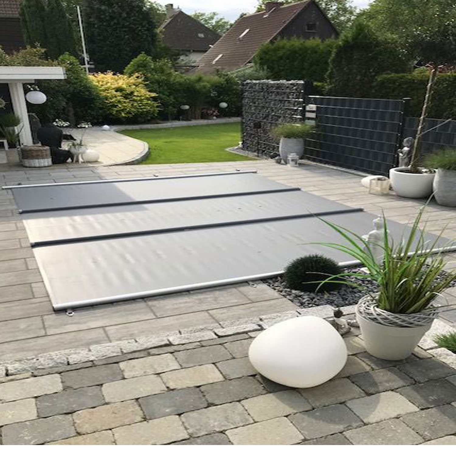 Abgebildet ist eine ausfahrbare Poolabdeckung, die Sicherheit und Schutz für den Poolbereich bietet.